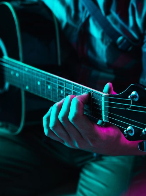 Close up of guitarist hand playing guitar, macro. Concept of advertising, hobby, music, festival, entertainment. Person improvising inspired. Copyspace to insert image or text. Colorful neon lighted.